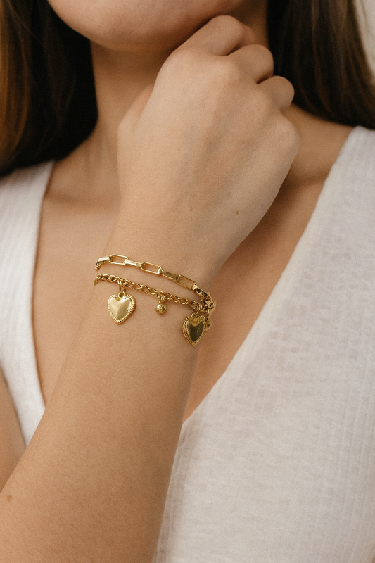 Femme portant un bracelet double chaîne doré avec petites perles pendantes et des cœurs - Rêve de Rose
