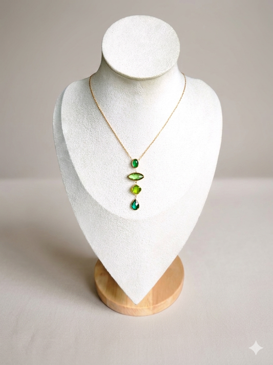 Collier Verdia – pendentif trio de cristaux verts sur chaîne dorée en acier inoxydable, présenté sur un buste blanc