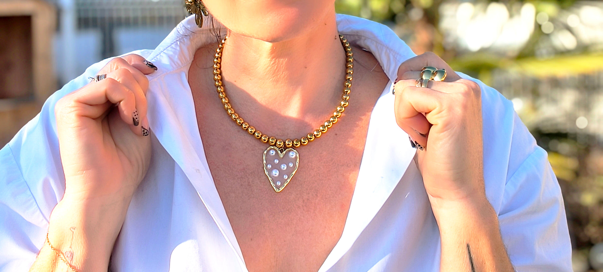 Femme portant Collier perles dorées avec pendentif cœur transparent avec perles blanches - Rêve de Rose