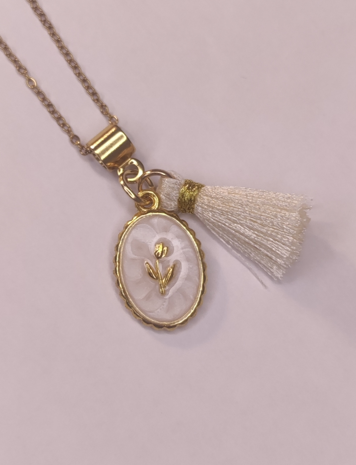 Détail d'un collier chaîne fine doré avec pendentifs pompon blanc et médaillon doré et blanc - Rêve de Rose