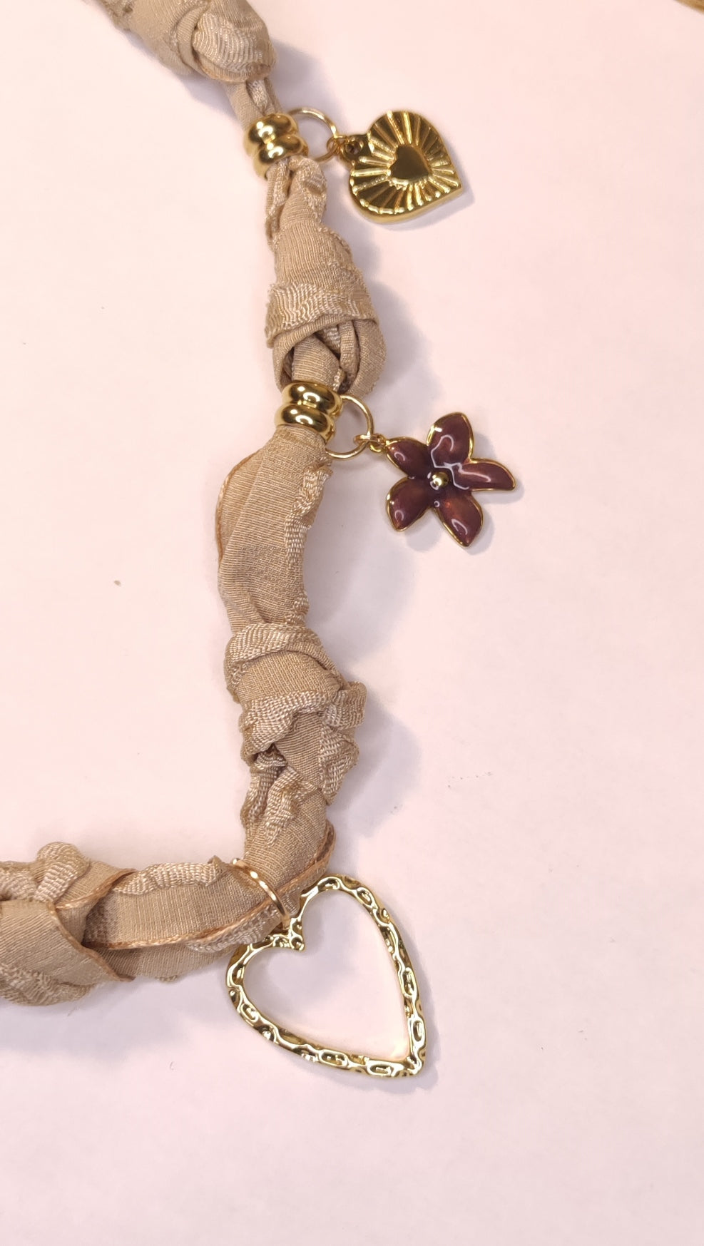 Détail d'un collier tissu beige avec 5 charms cœurs marrons et dorés - Rêve de Rose