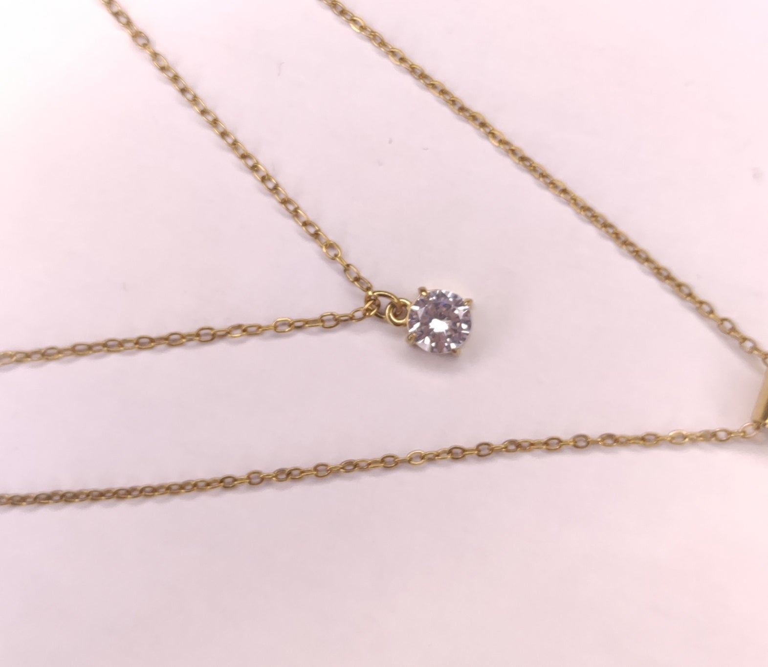 Détail d'un collier triple chaîne avec petites perles dorées pendantes, un pendentif pierre scintillante et un pendentif rond avec une étoile scintillante - Rêve de Rose 