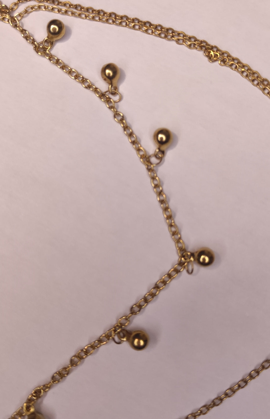Détail d'un collier triple chaîne avec petites perles dorées pendantes, un pendentif pierre scintillante et un pendentif rond avec une étoile scintillante - Rêve de Rose 