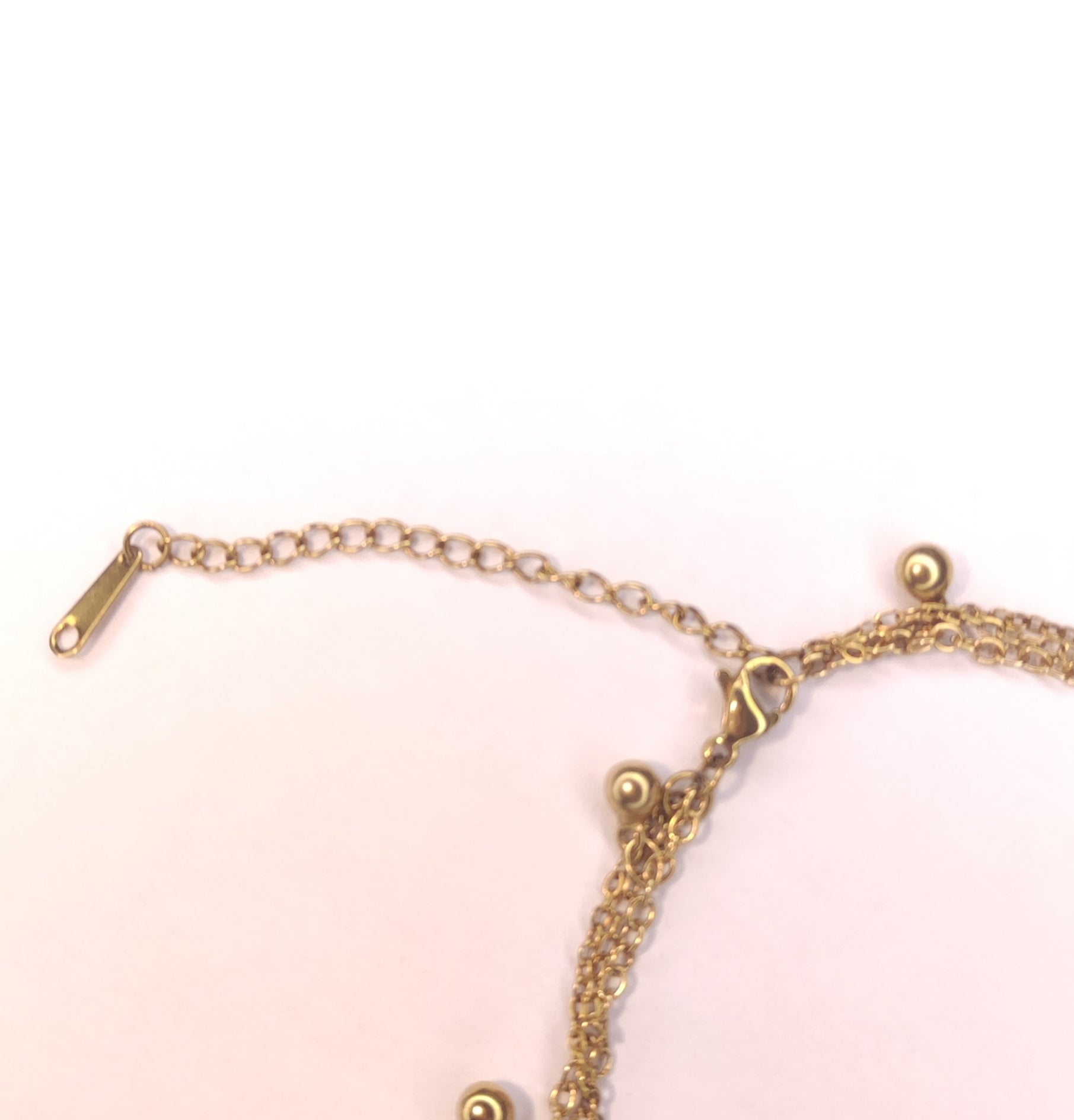 Fermoir d'un collier triple chaîne avec petites perles dorées pendantes, un pendentif pierre scintillante et un pendentif rond avec une étoile scintillante - Rêve de Rose 