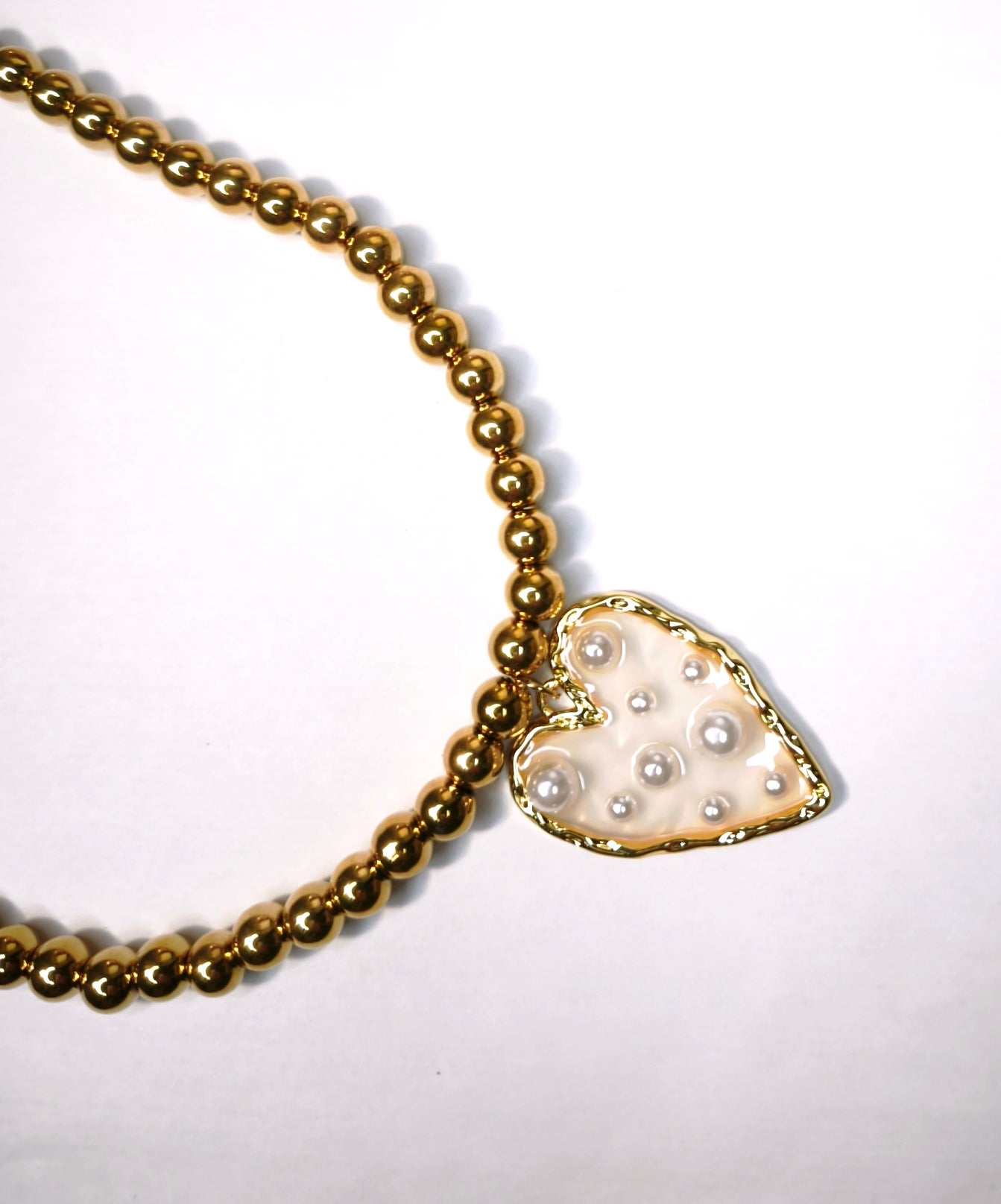 Détail d'un collier perles dorées avec pendentif cœur transparent avec perles blanches - Rêve de Rose