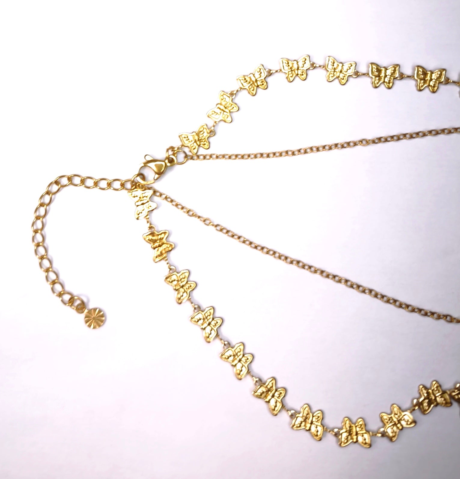Détail d'un collier double chaîne doré une fine et une sertie de papillons avec un pendentif papillon doré - Rêve de Rose 
