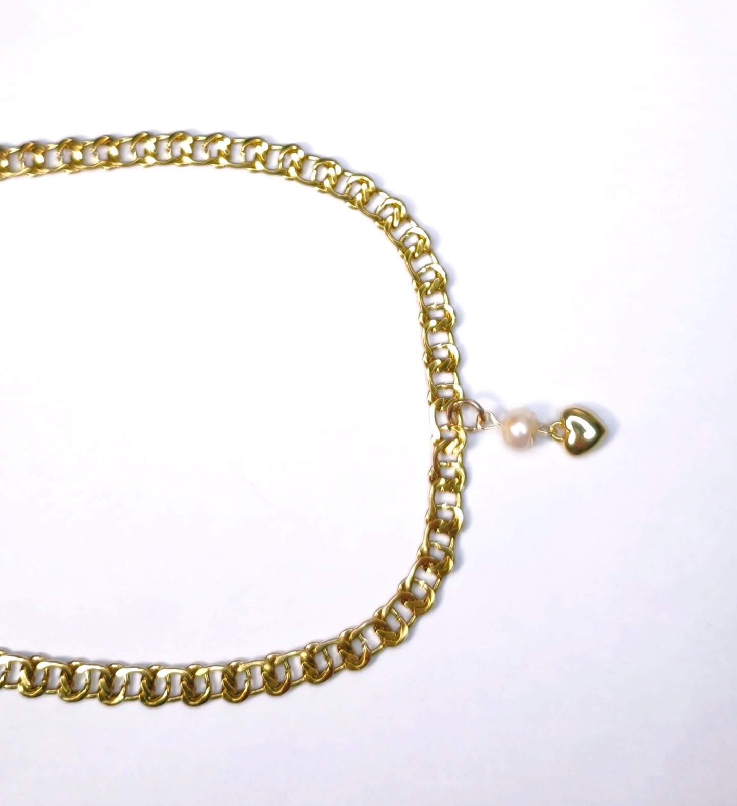 Détail d'un collier chaîne dorée aux maillons serrés avec pendentif perle blanche et un petit cœur doré - Rêve de Rose