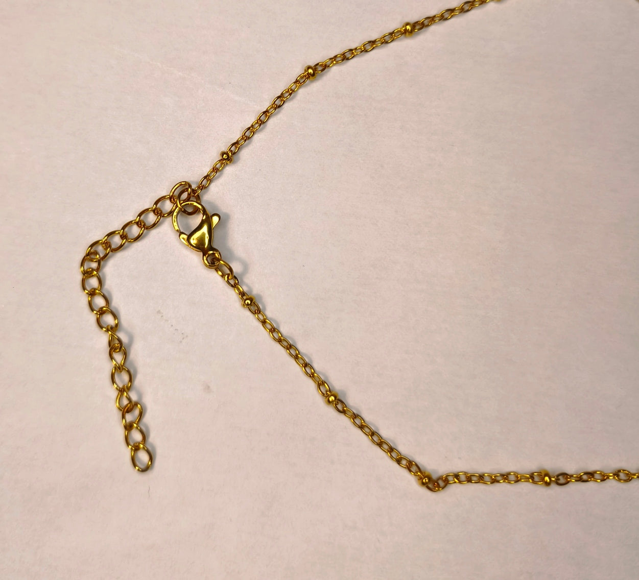Fermoir d'un collier doré Y avec petit cœur et un petit nœud doré en bas  - Rêve de Rose
