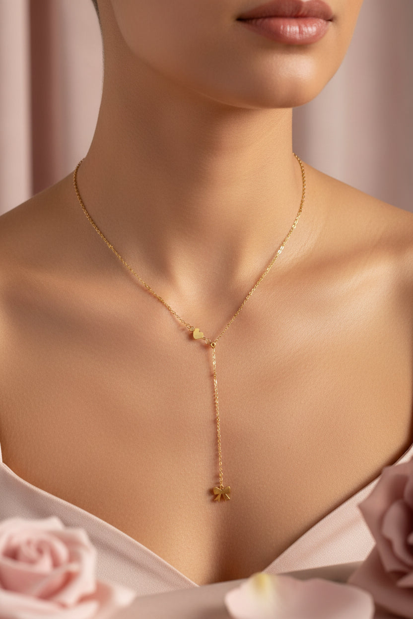 Femme portant un collier doré Y avec petit cœur et un petit nœud doré en bas  - Rêve de Rose