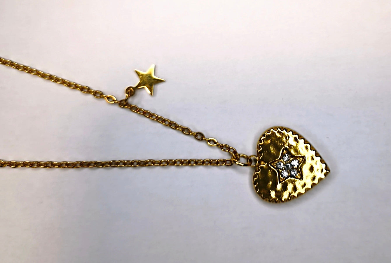 Détail d'un collier chaîne fine dorée avec une petite étoile et un pendentif cœur - Rêve de Rose