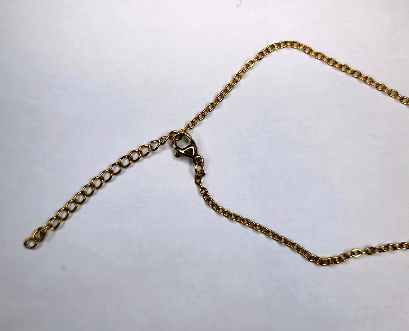 Fermoir d'un collier chaîne fine dorée avec une petite étoile et un pendentif cœur - Rêve de Rose