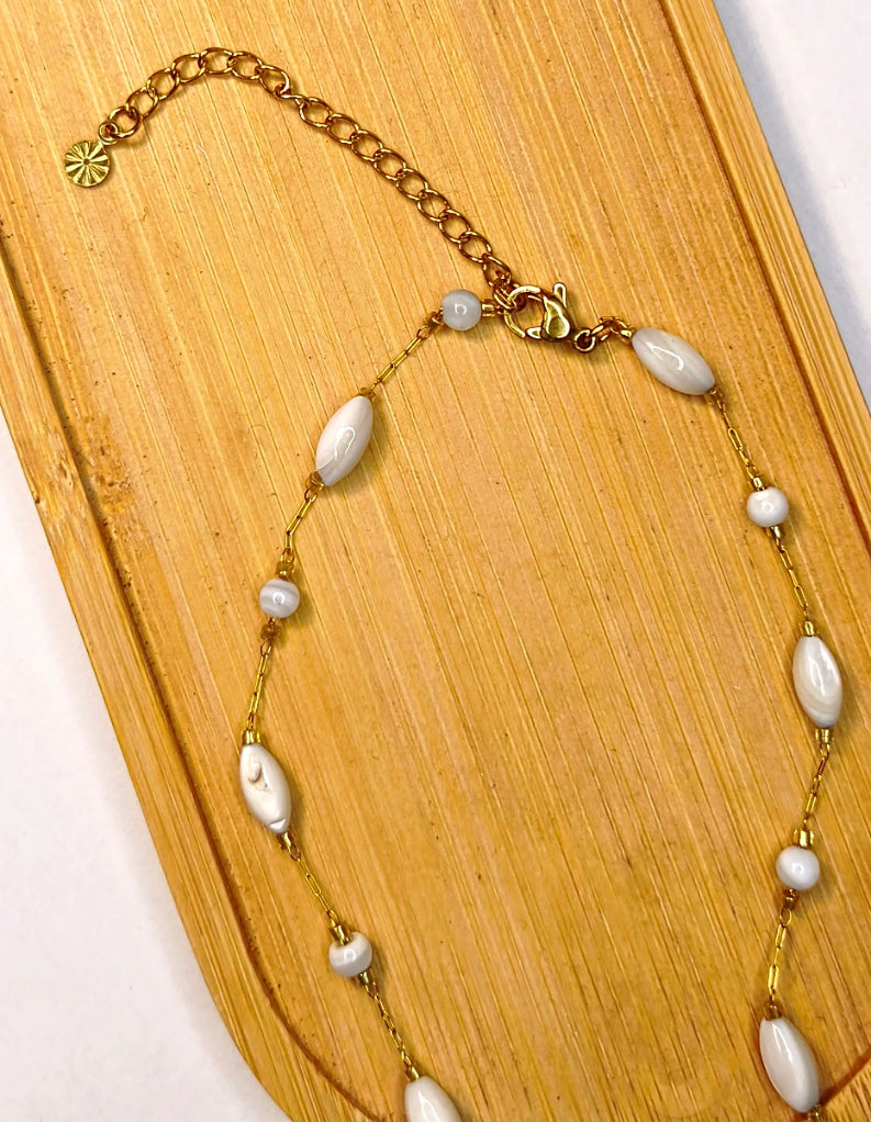 Détail d'un collier chaîne dorée avec des perles blanches avec un pendentif fleur dorée - Rêve de Rose