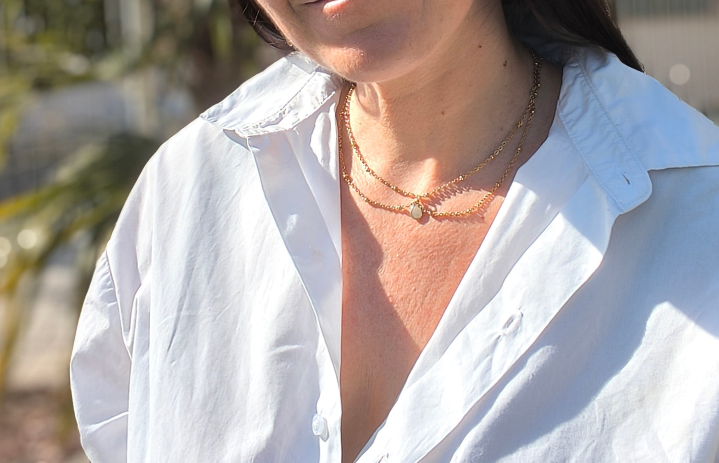 Femme portant Collier double chaîne dorée avec pendentif pierre verte pastel au centre - Rêve de Rose