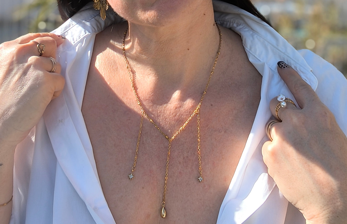 Femme portant Collier avec 3 chaînes pendantes, 2 petites étoiles scintillantes au bout et une larme dorée - Rêve de Rose