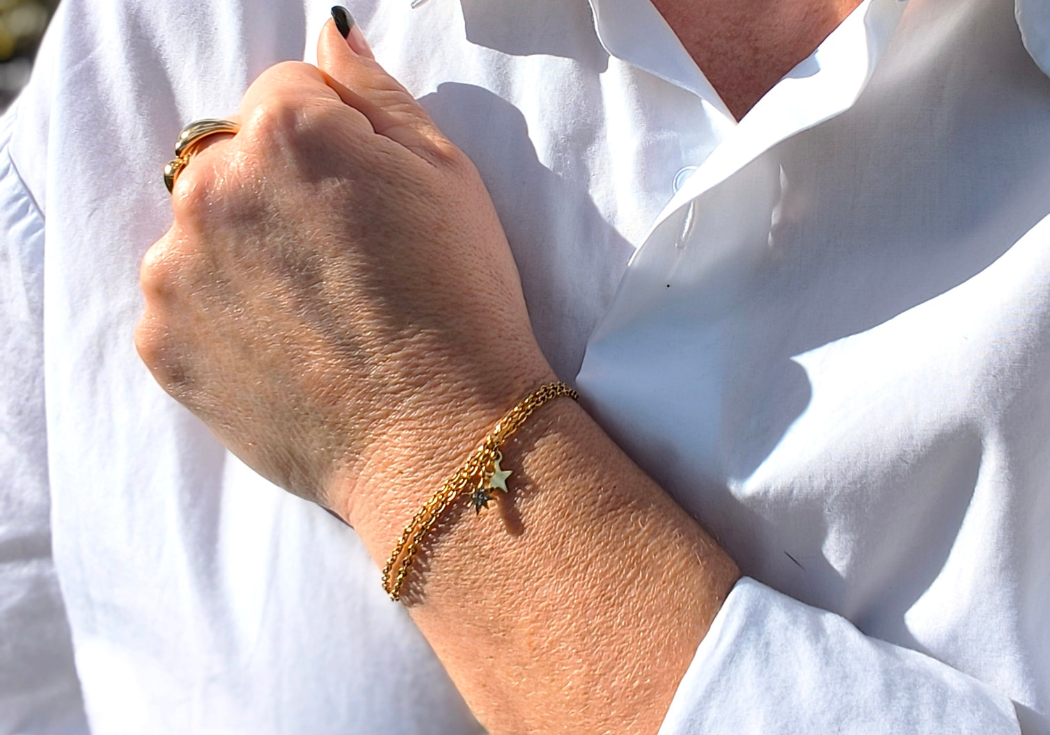 Femme portant Bracelet double chaîne doré avec une  petite étoile scintillante et une petite étoile dorée - Rêve de Rose