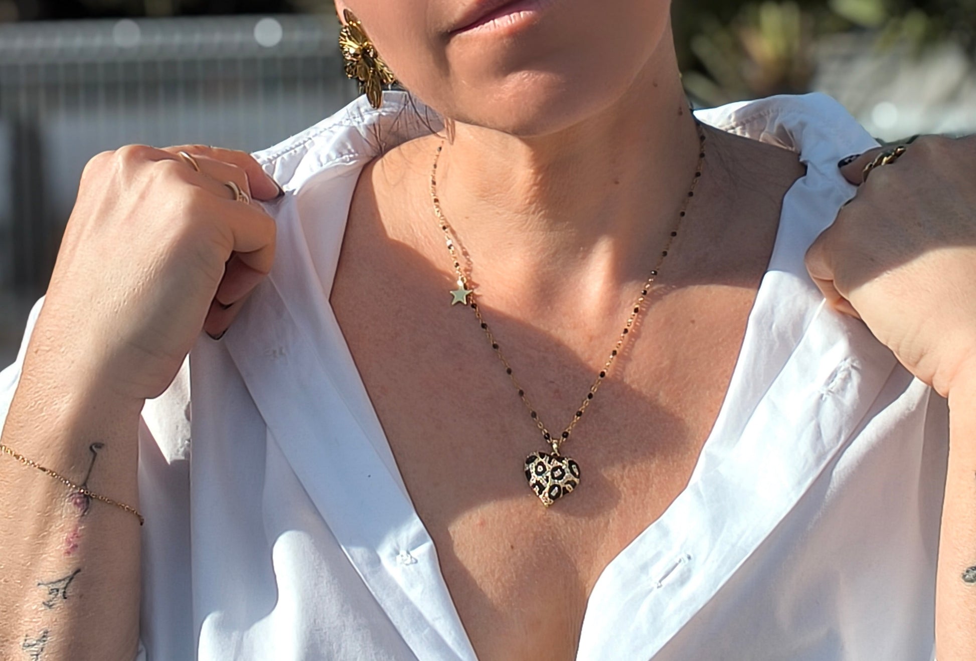 Femme portant Collier chaîne doré et noire avec un gros cœur noir et doré au motif léopard et un petit pendentif étoile dorée - Rêve de Rose