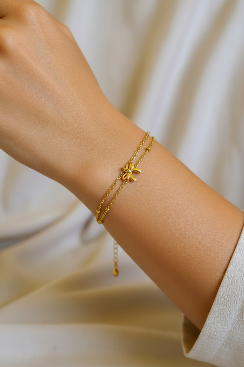 Bracelet double chaîne doré avec perles et charm nœud porté au poignet - création artisanale Rêve de Rose