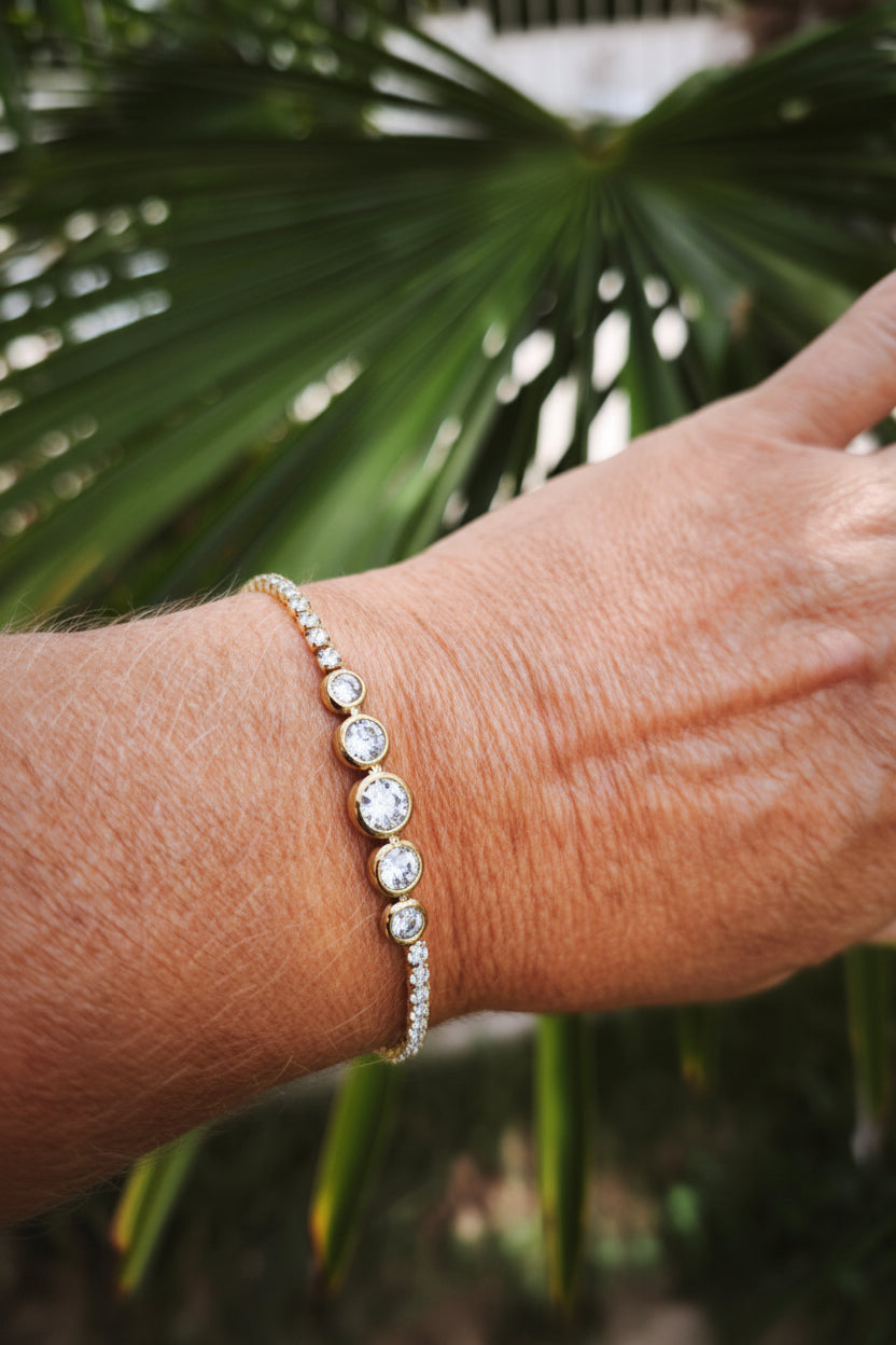 Bracelet tennis doré en acier inoxydable avec trois zircons cubiques sertis clos et chaîne pavée, présenté sur un poignet - Rêve de Rose