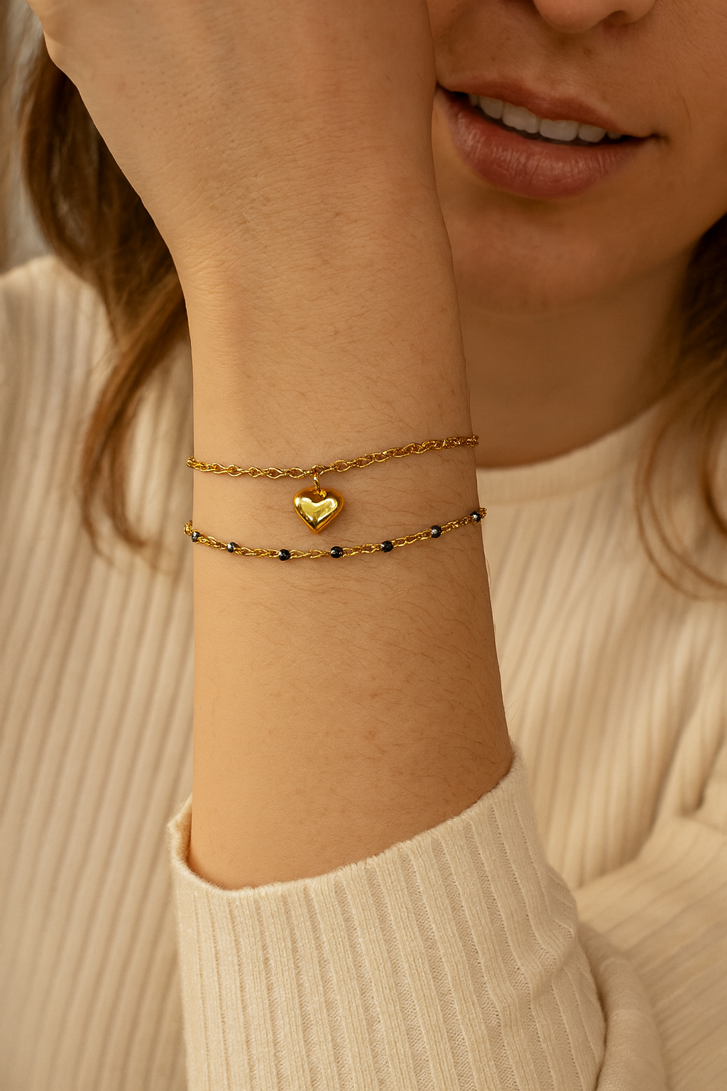 Femme portant un bracelet double chaîne doré et noir avec pendentif cœur doré - Rêve de Rose