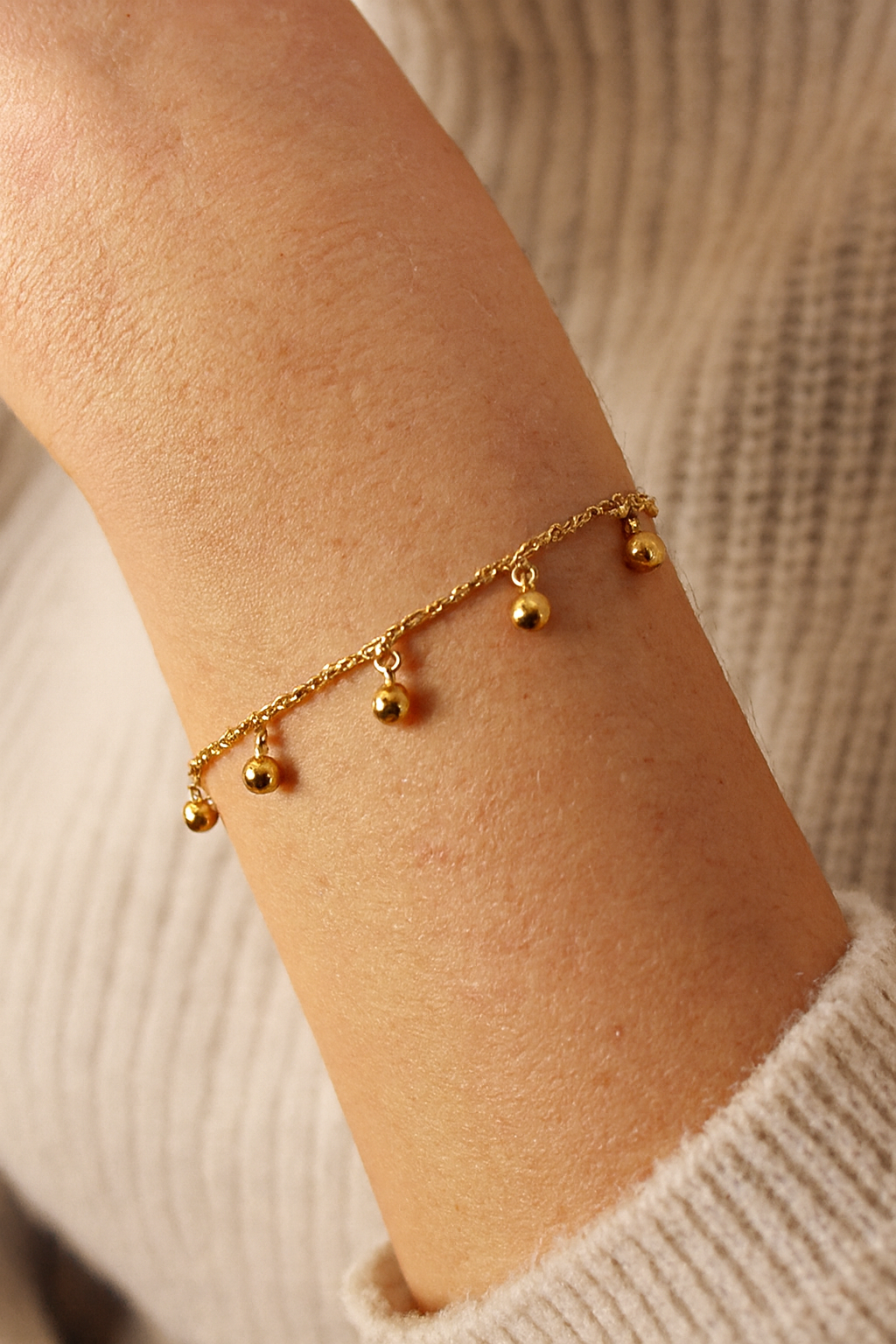 Femme portant un bracelet chaîne fine avec des petites perles dorées pendantes - Rêve de Rose